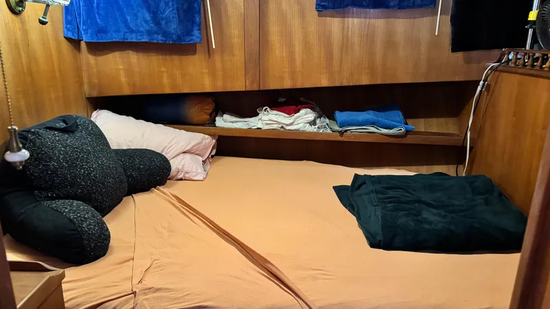 Slide: The Image of 1977 Marine Trader Europa cabin with cozy bed, pillows, and wooden storage shelves. - 16