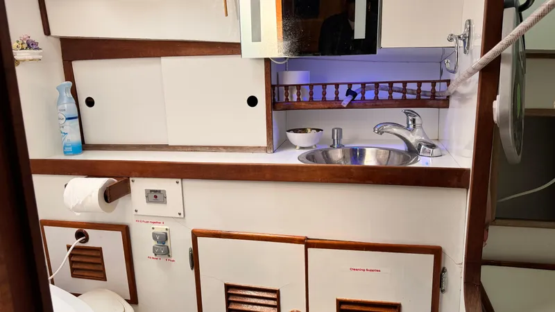 Slide: The Image of 1977 Marine Trader Europa bathroom with sink, storage cabinets, and toiletries. - 18