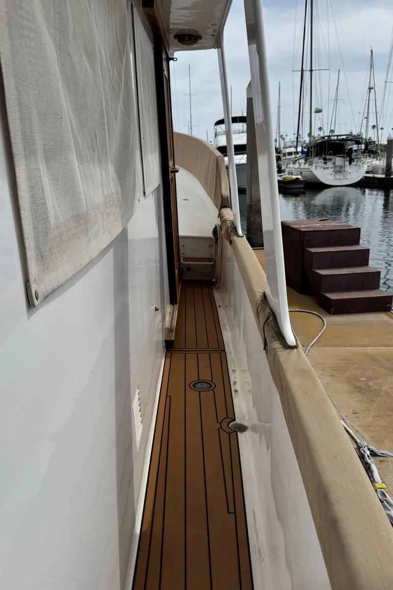 Slide: The Image of 1977 Marine Trader Europa yacht docked at marina, showcasing side deck and railing. - 23