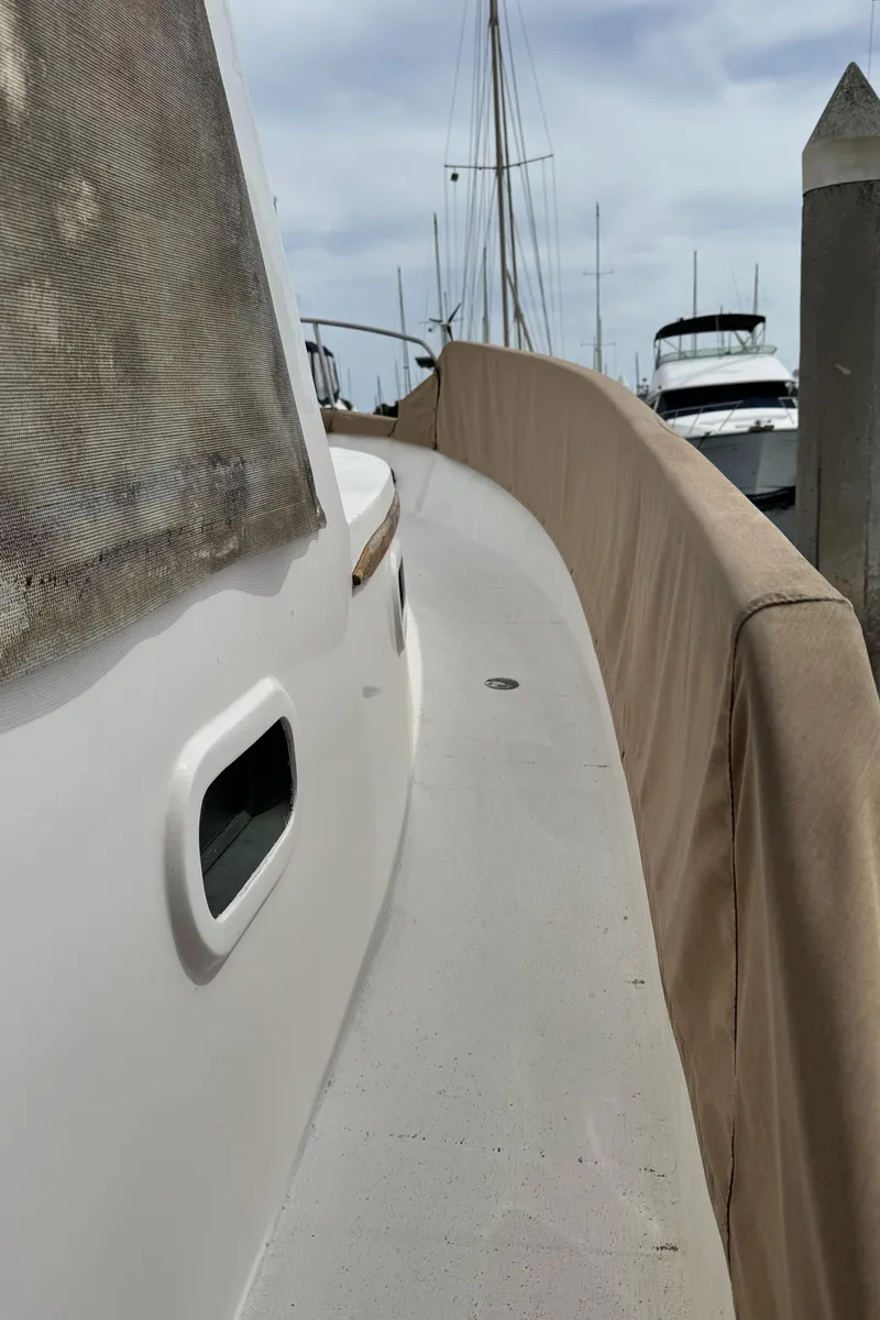 Slide: The Image of 1977 Marine Trader Europa yacht docked, showcasing side deck and railing. - 24