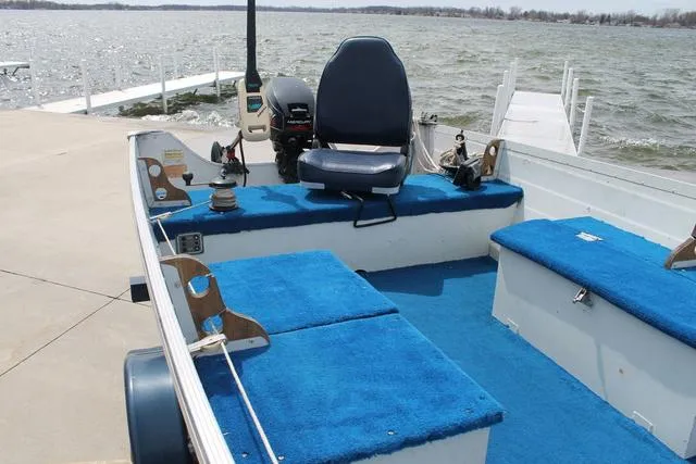 Slide: The Image of 1998 Smoker Craft BIG FISH boat with blue interior, docked by a lake. - 12