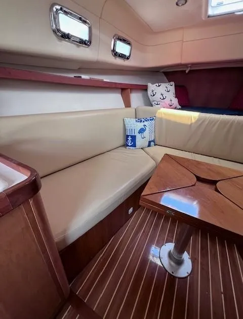 Slide: The Image of 2004 Mainship 30 Pilot Rum Runner cabin with beige seating and wooden table. - 14