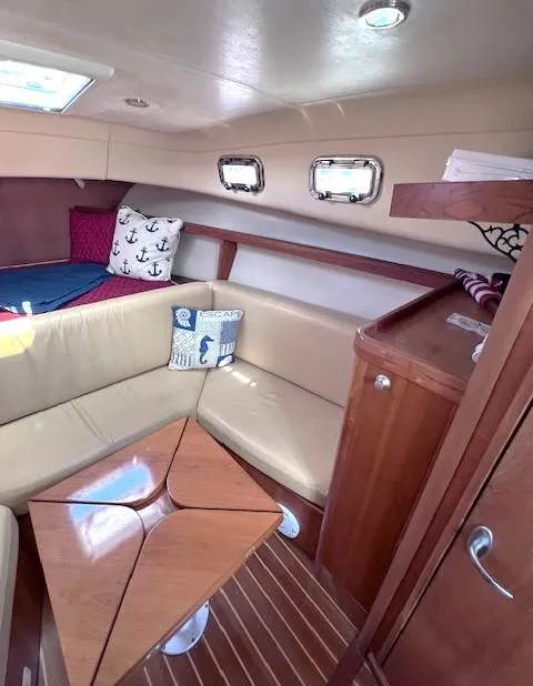 Slide: The Image of 2004 Mainship 30 Pilot Rum Runner cabin with beige seating and wooden table. - 15