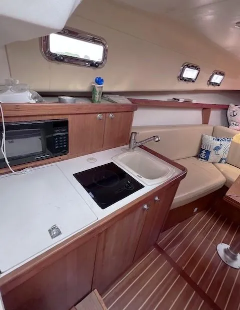 Slide: The Image of 2004 Mainship 30 Pilot Rum Runner interior with kitchenette, sink, and seating area. - 16