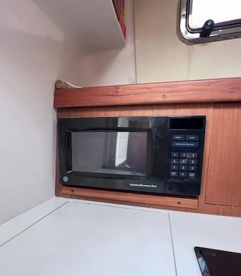 Slide: The Image of Microwave in 2004 Mainship 30 Pilot Rum Runner boat interior, wooden cabinetry, compact design. - 18