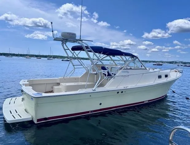 Slide: The Image of 2004 Mainship 30 Pilot Rum Runner boat on calm water under blue sky. - 2