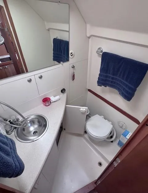 Slide: The Image of 2004 Mainship 30 Pilot Rum Runner bathroom with sink, toilet, and blue towel. - 21