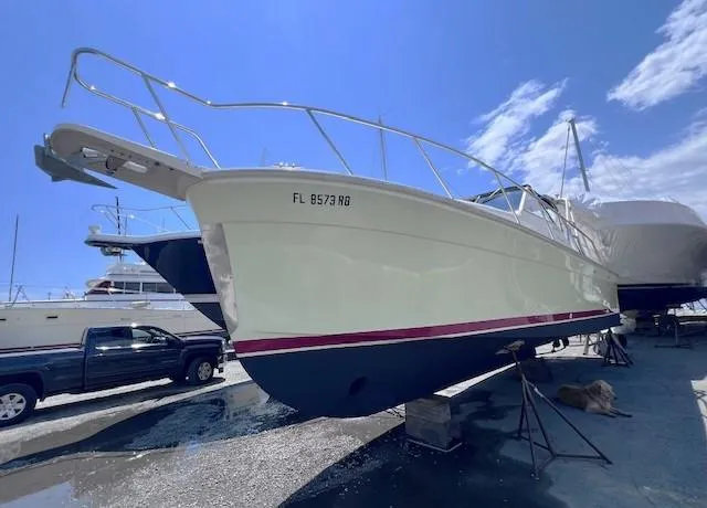 Slide: The Image of 2004 Mainship 30 Pilot Rum Runner boat on dry dock under clear blue sky. - 3