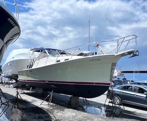 Slide: The Image of 2004 Mainship 30 Pilot Rum Runner boat on stands, under a cloudy sky. - 4