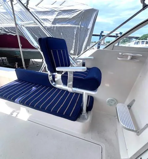 Slide: The Image of 2004 Mainship 30 Pilot Rum Runner boat with blue-striped seating and helm area. - 8