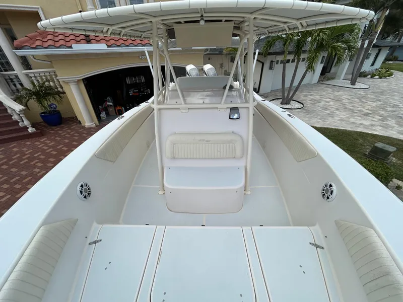 Slide: The Image of 2002 Grady-White 306 Bimini boat, spacious deck, white seating, and canopy, parked near a house. - 11
