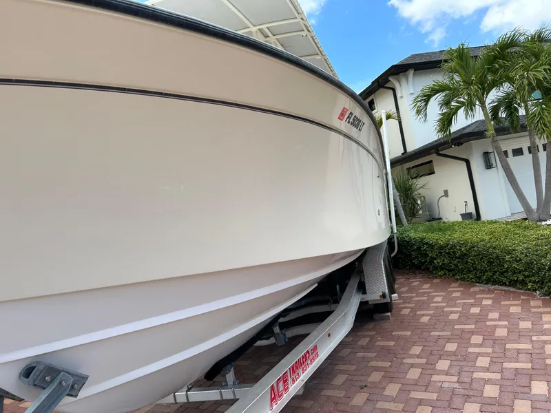 Slide: The Image of 2002 Grady-White 306 Bimini boat on trailer, parked in a driveway with palm trees. - 5