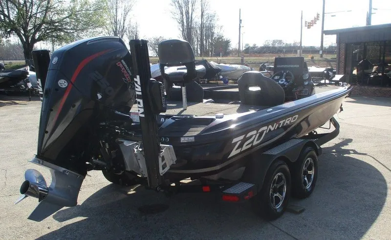 Slide: The Image of 2019 Nitro Z20 boat with powerful outboard motor, parked on a trailer in a sunny outdoor setting. - 2