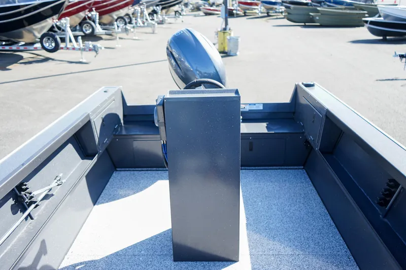 Slide: The Image of 2025 Alumaweld Adventurer 20 boat interior with motor, parked among other boats. - 9