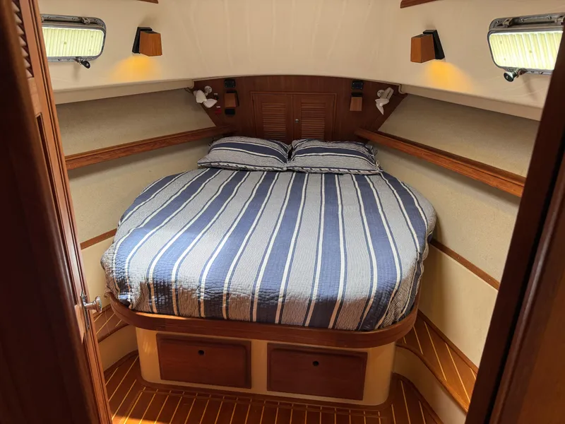 Slide: The Image of Island Packet 380 yacht cabin interior with striped bedding, wood accents, and soft lighting, 2002 model. - 11