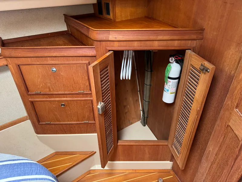 Slide: The Image of Wooden interior storage with open cabinet, hangers, and fire extinguisher on Island Packet 380 yacht. - 13