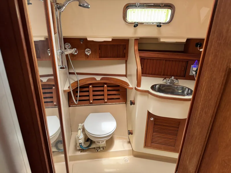 Slide: The Image of Island Packet 380 yacht bathroom, 2002 model, featuring wooden cabinetry, toilet, sink, and shower. - 14
