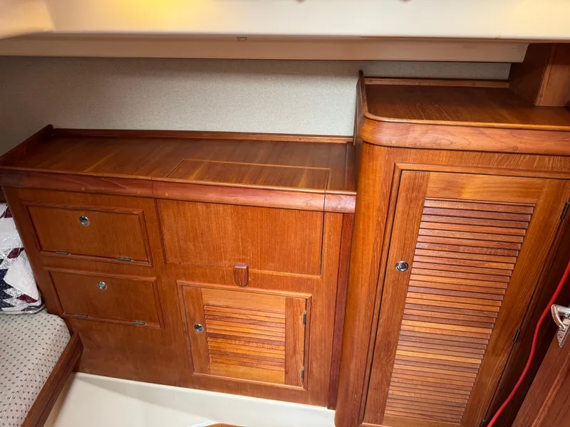 Slide: The Image of Wooden cabinetry inside a 2002 Island Packet 380 sailboat, featuring drawers and a louvered door. - 16