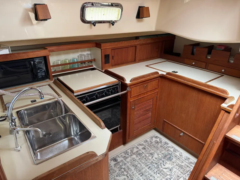 Slide: The Image of Interior of 2002 Island Packet 380 sailboat kitchen with sink, stove, and wooden cabinetry. - 17