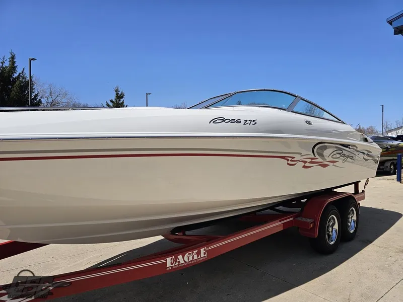 Slide: The Image of 2004 Baja 275 boat on a red trailer, parked outdoors under a clear blue sky. - 20