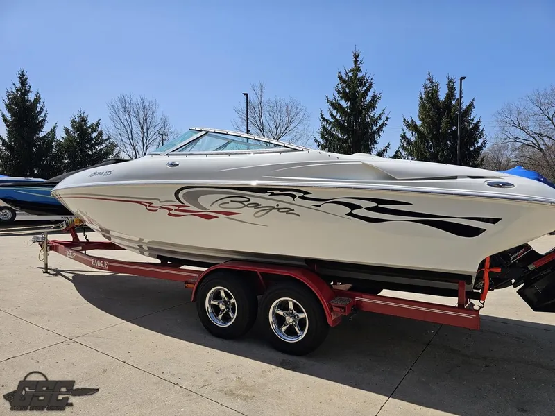 Slide: The Image of 2004 Baja 275 boat on a red trailer, parked outdoors with trees in the background. - 25