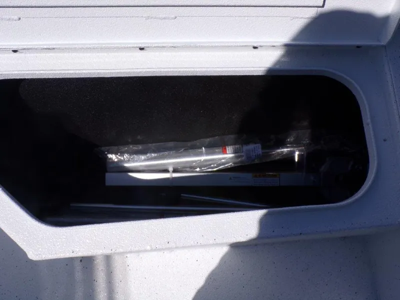 Slide: The Image of Storage compartment in a 2025 Xpress H20BAY boat, partially open with equipment inside. - 13