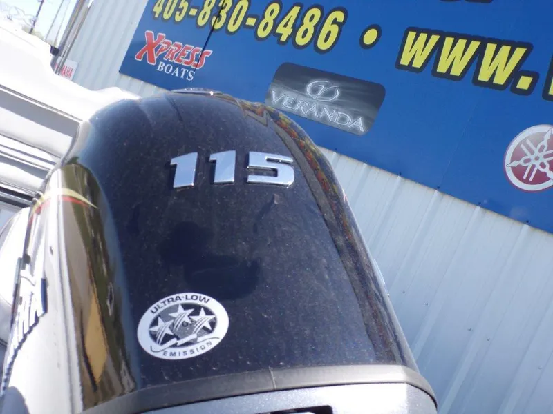 Slide: The Image of Outboard motor with "115" label, ultra-low emission sticker, Xpress Boats sign in background. - 2