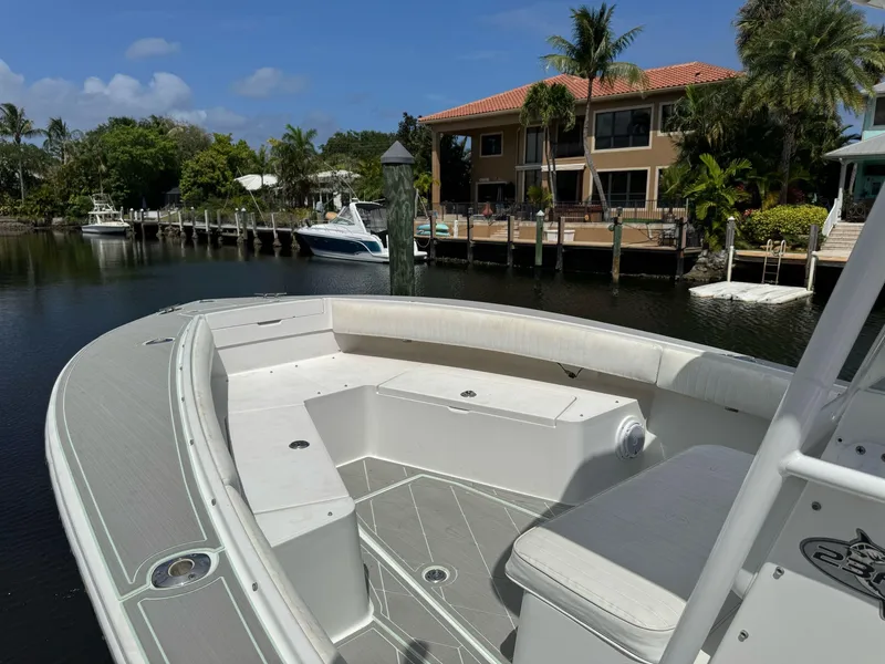 Slide: The Image of 2022 Pursuit S 288 boat docked near waterfront homes, surrounded by palm trees. - 10