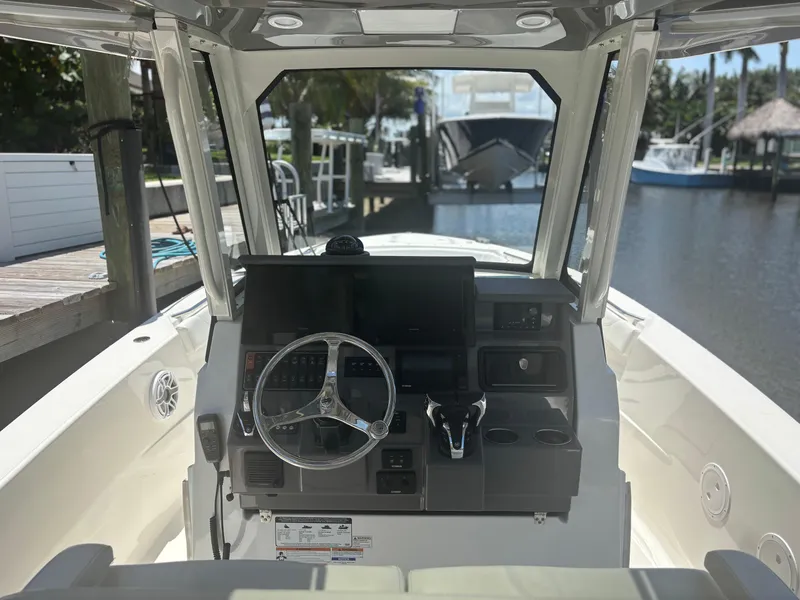 Slide: The Image of 2022 Pursuit S 288 boat helm with steering wheel and controls, docked by a marina. - 18