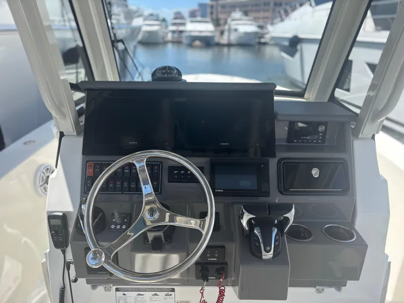 Slide: The Image of 2022 Pursuit S 288 boat dashboard with steering wheel and controls, docked at marina. - 20
