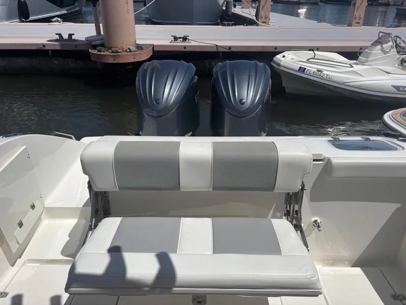 Slide: The Image of 2022 Pursuit S 288 boat with dual engines and cushioned seating at a marina. - 25