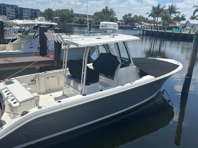 Slide: The Image of 2022 Pursuit S 288 boat docked in a marina with palm trees in the background. - 4