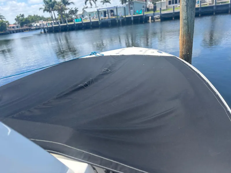 Slide: The Image of 2022 Pursuit S 288 boat with black cover docked by waterfront homes. - 6