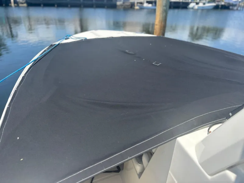 Slide: The Image of 2022 Pursuit S 288 boat with a black cover, docked by the water. - 7