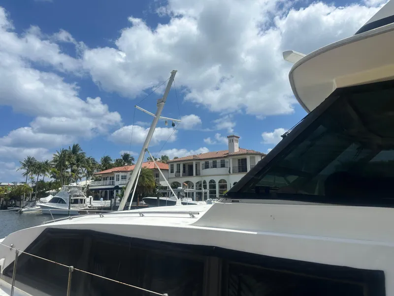 Slide: The Image of 1974 Bertram 42 Motor Yacht docked near waterfront homes under a partly cloudy sky. - 10