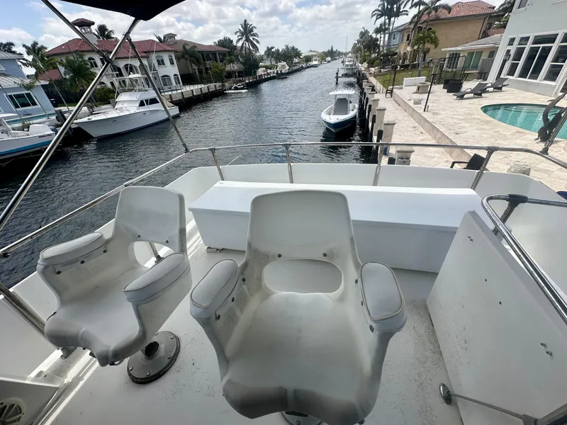 Slide: The Image of 1974 Bertram 42 Motor Yacht deck with chairs, overlooking a canal and waterfront homes. - 11