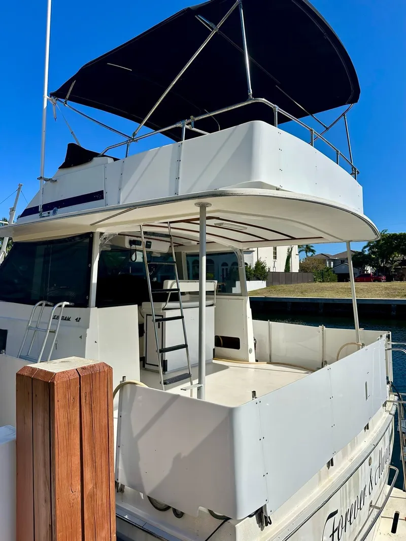 Slide: The Image of 1974 Bertram 42 Motor Yacht with canopy, docked under clear blue sky. - 12