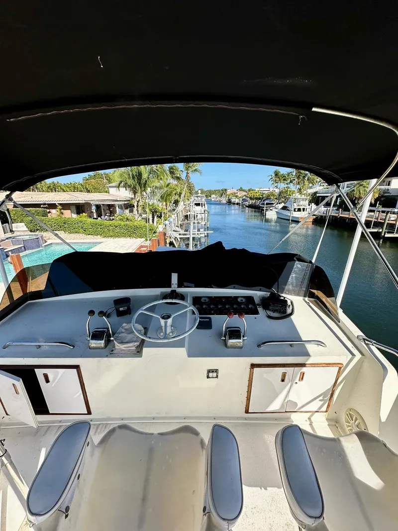 Slide: The Image of 1974 Bertram 42 Motor Yacht helm with canal view, featuring classic controls and seating. - 14