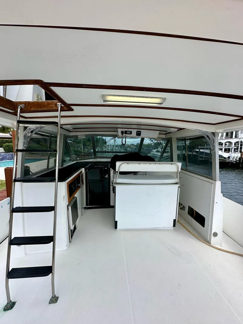 Slide: The Image of 1974 Bertram 42 Motor Yacht interior with helm, seating, and ladder, docked by the water. - 15