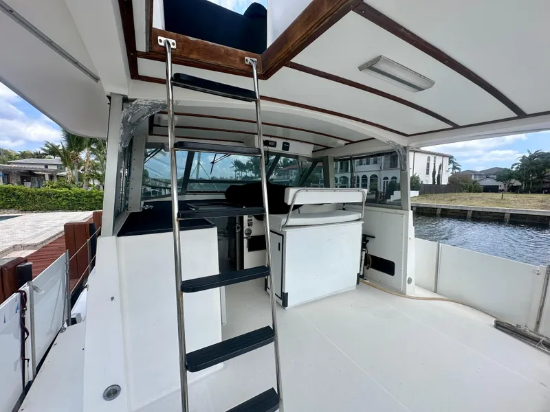 Slide: The Image of 1974 Bertram 42 Motor Yacht interior with ladder, spacious deck, and waterfront view. - 16
