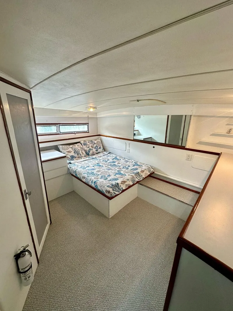 Slide: The Image of 1974 Bertram 42 Motor Yacht cabin with bed, white interior, and wood accents. - 25