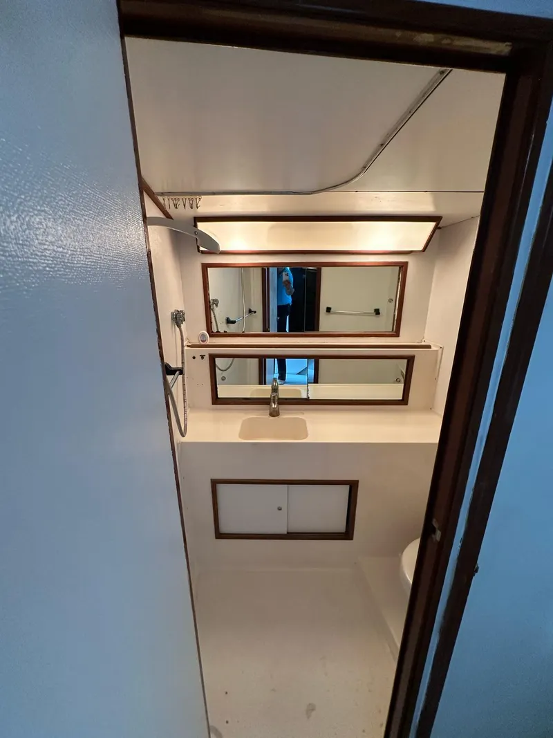 Slide: The Image of 1974 Bertram 42 Motor Yacht bathroom with mirror, sink, and storage cabinets. - 27