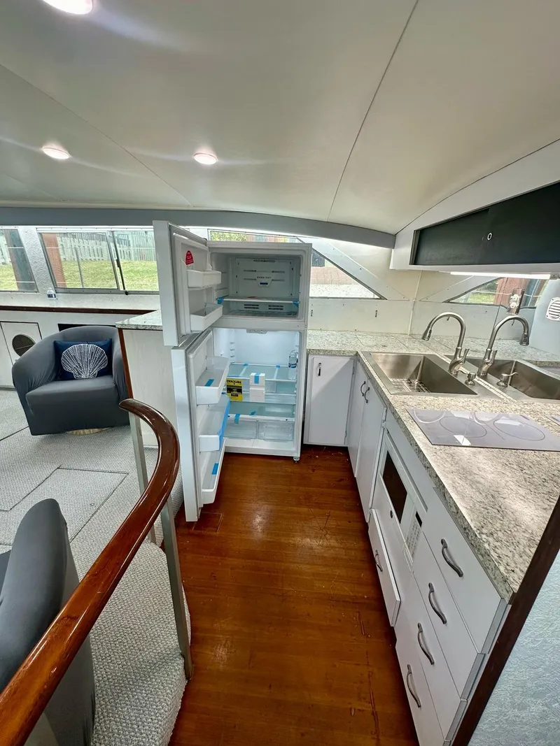 Slide: The Image of 1974 Bertram 42 Motor Yacht interior with open fridge, modern kitchen, and seating area. - 28