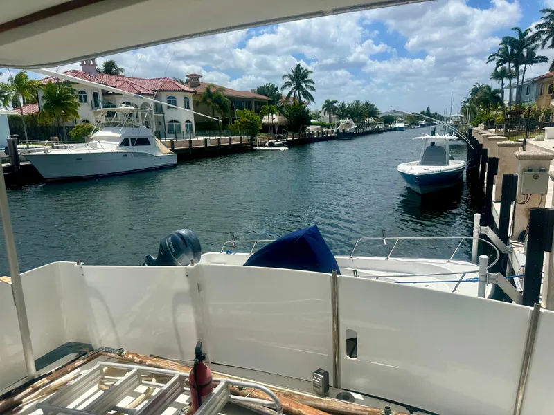 Slide: The Image of 1974 Bertram 42 Motor Yacht docked in a scenic canal with palm trees and luxury homes. - 30