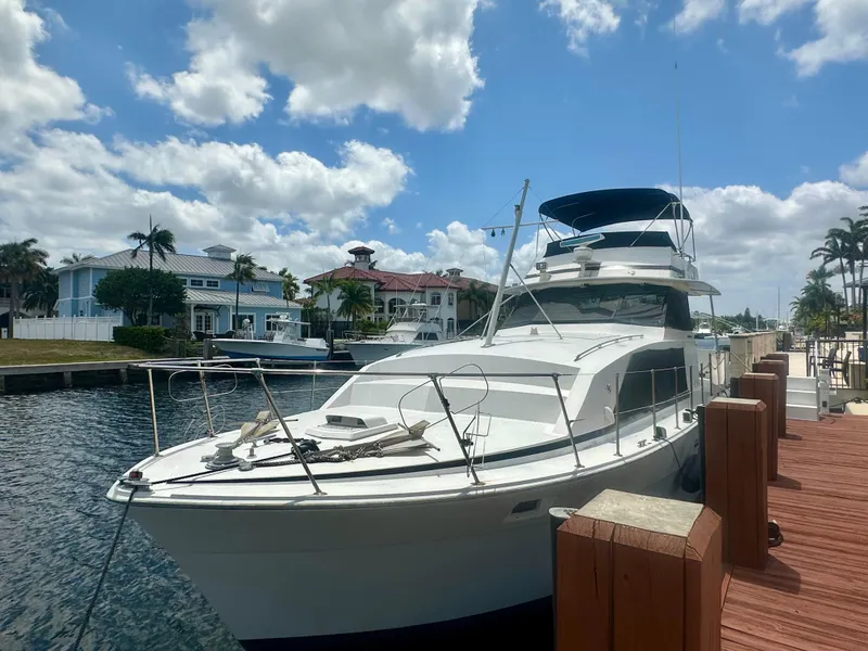 Slide: The Image of 1974 Bertram 42 Motor Yacht docked by waterfront homes under a partly cloudy sky. - 4