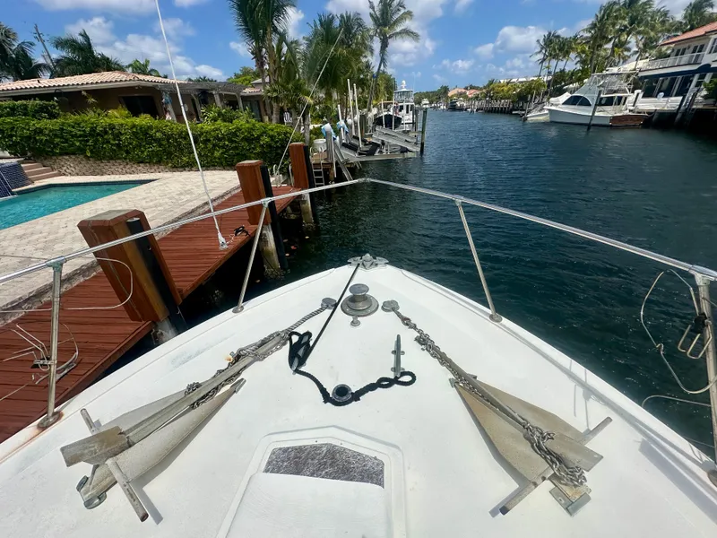 Slide: The Image of 1974 Bertram 42 Motor Yacht docked by a scenic canal with palm trees and clear skies. - 7