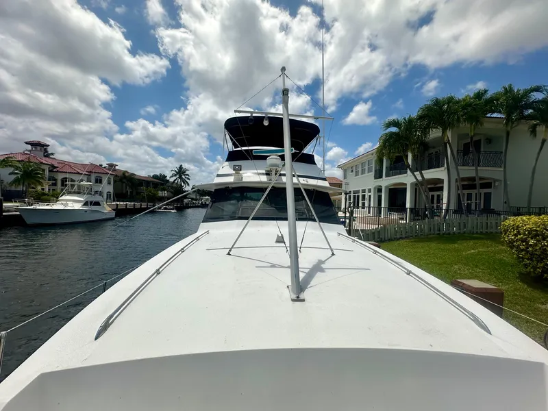 Slide: The Image of 1974 Bertram 42 Motor Yacht docked by waterfront homes under a partly cloudy sky. - 8