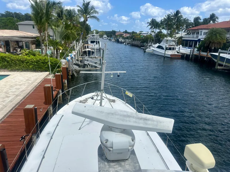 Slide: The Image of 1974 Bertram 42 Motor Yacht docked in a scenic canal with palm trees and blue sky. - 9