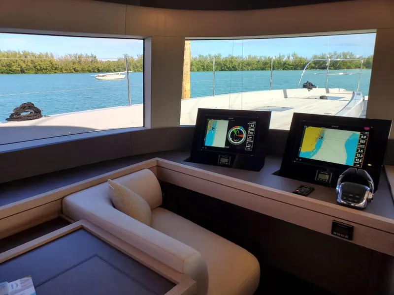 Slide: The Image of Interior view of 2020 Lagoon SEVENTY 7 yacht with navigation screens and scenic water view. - 3