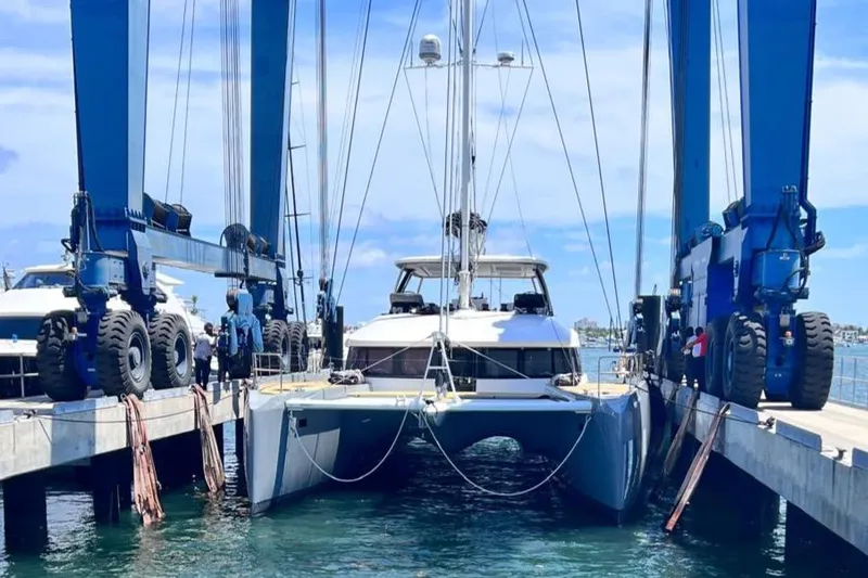 Slide: The Image of 2020 Lagoon SEVENTY 7 catamaran in dry dock, surrounded by blue cranes. - 40